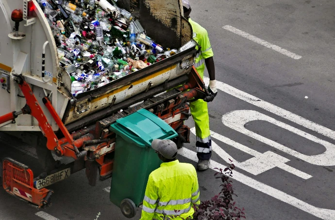 people collecting trash in garbage truck